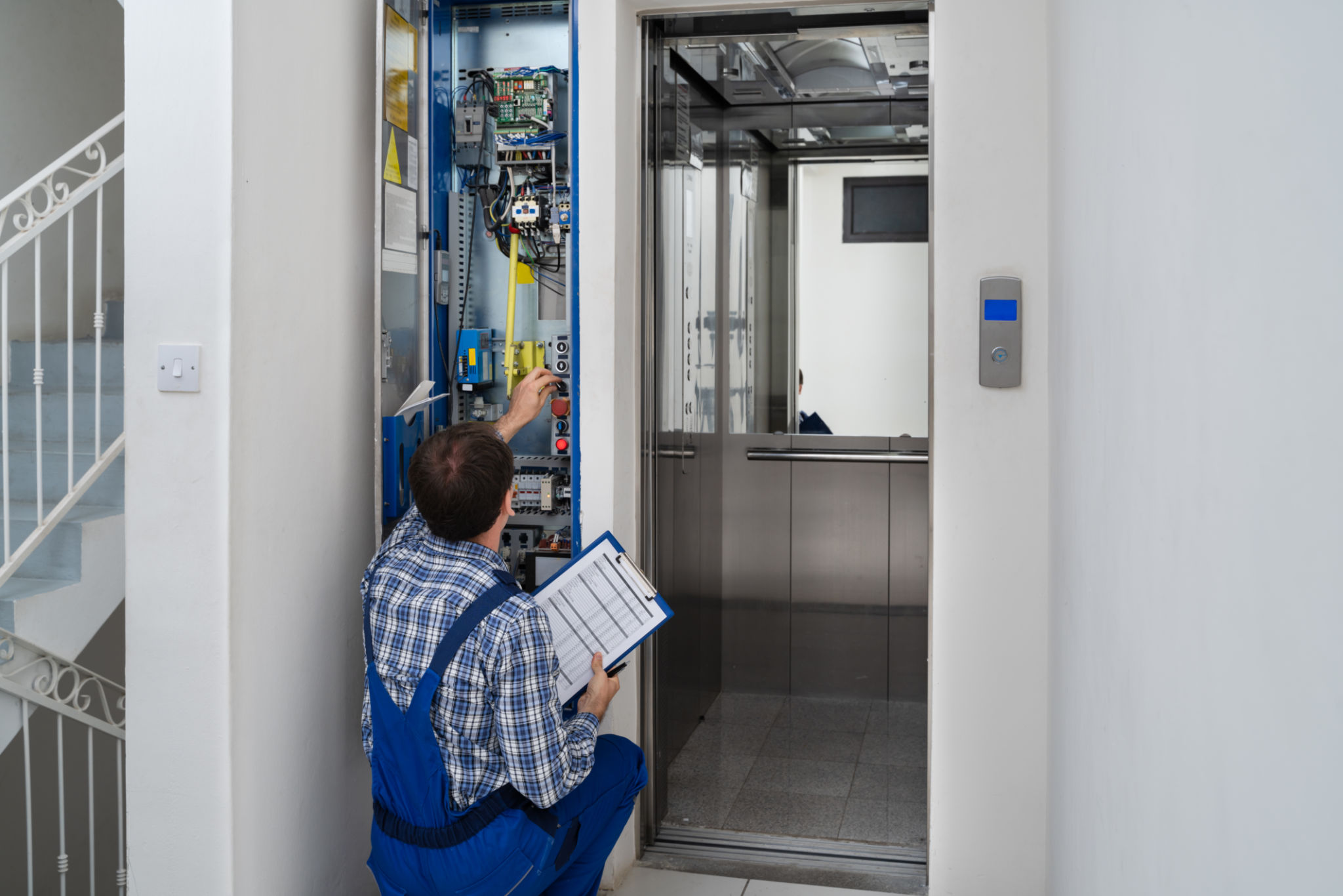Technician Repairing Control Panel Of Broken Elevator