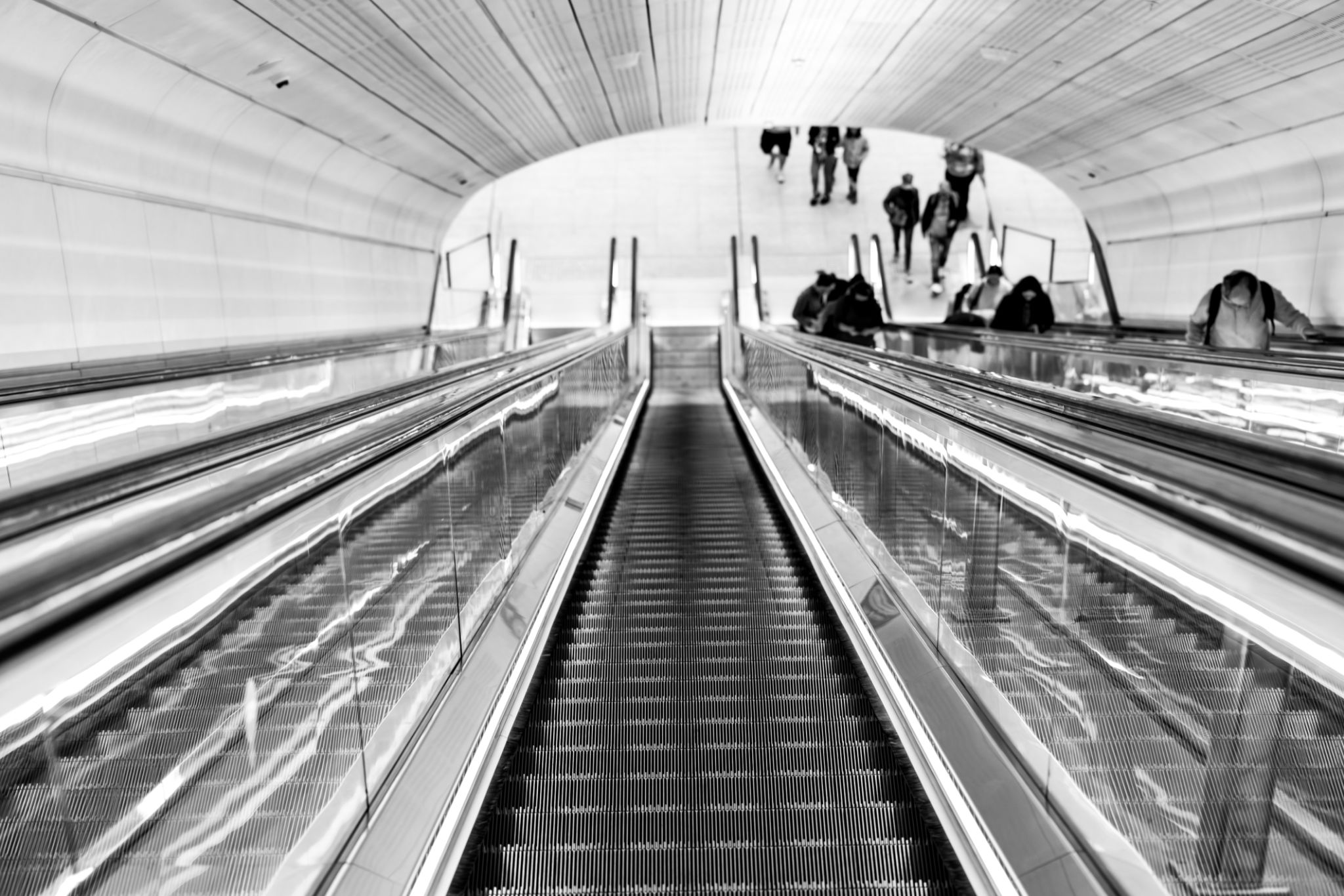 People traveling on escalator, black and white, background with copy space, full frame horizontal composition